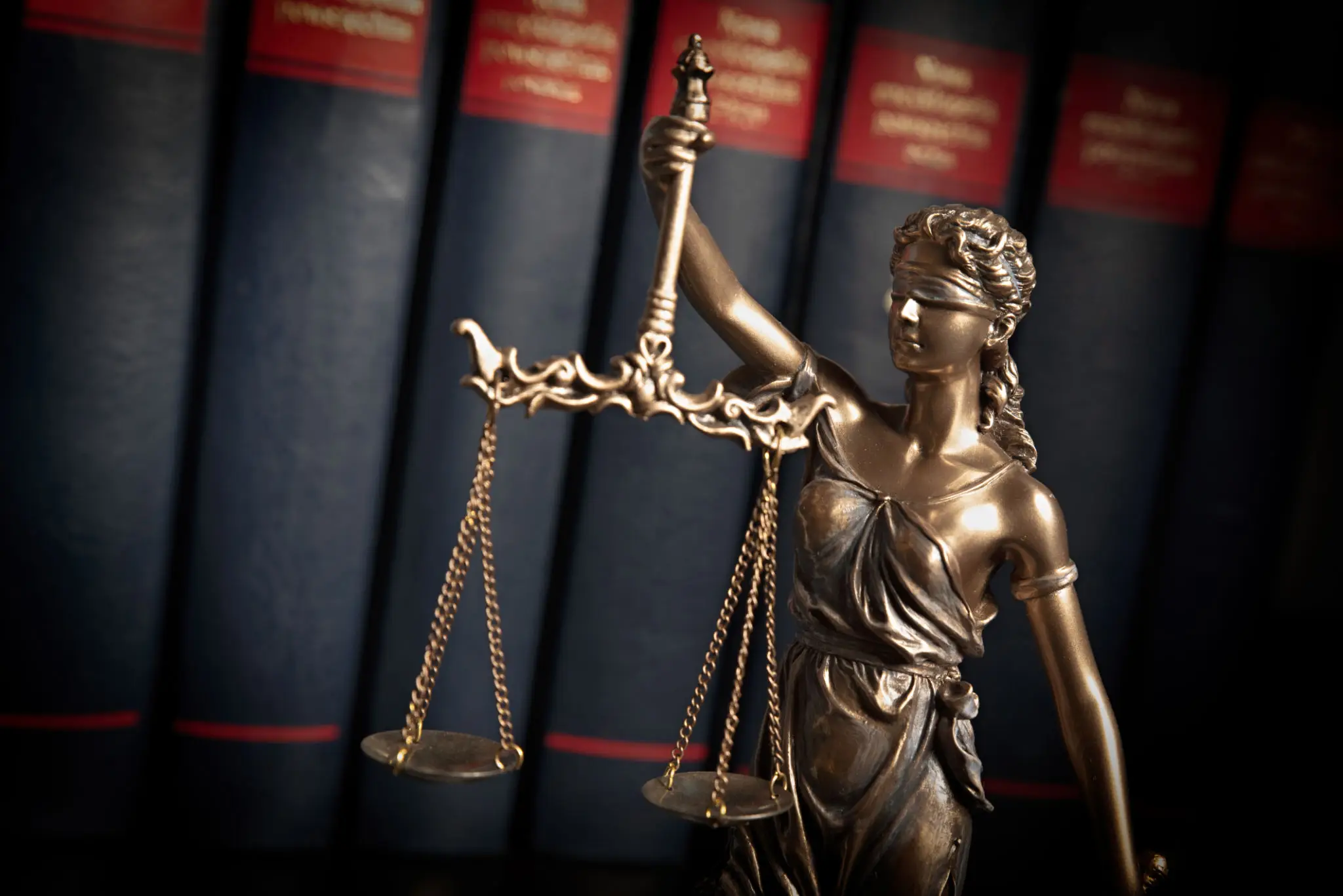 Bronze Lady Justice statue with law books in background.